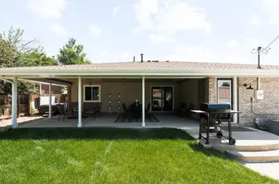 a covered patio with a table and a grill at Fam Retreat, Hot Tub, BBQ, Ski, Game Room, Backyard in Arvada