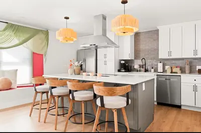 a kitchen with white cabinets and a counter with bar stools at Fam Retreat, Hot Tub, BBQ, Ski, Game Room, Backyard in Arvada