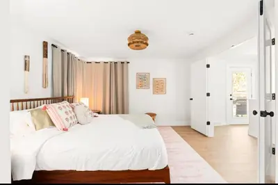 a bedroom with a bed with white sheets and pink pillows at Fam Retreat, Hot Tub, BBQ, Ski, Game Room, Backyard in Arvada