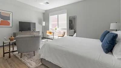a bedroom with a bed and a television and a chair at Landing Chic Studio in Fort Collins in Fort Collins
