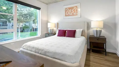 a bedroom with a bed with two lamps and a window at Landing Stunning Studio Rooftop Lounge Gym in Englewood