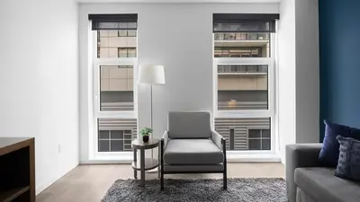 a living room with a chair and two windows at Landing Beautiful 1BD Gym Rooftop Lounge in Denver