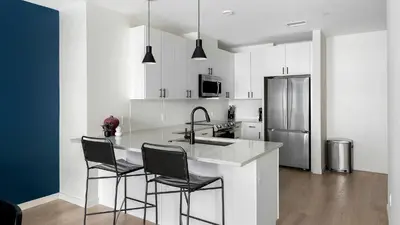 a kitchen with a counter with chairs and a refrigerator at Landing Beautiful 1BD Gym Rooftop Lounge in Denver