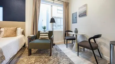 a bedroom with a bed and a chair and a table at Landing Modern Studio Rooftop Lounge in Denver