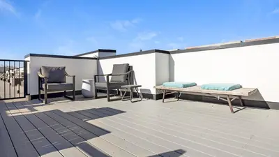 a patio with two chairs and a bench on a roof at Landing Modern Studio Rooftop Lounge in Denver