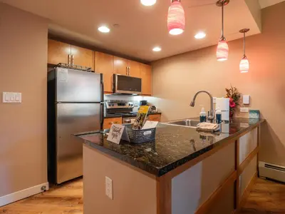 a kitchen with a stainless steel refrigerator and a sink at Fraser Crossing 1BR Condo | Hot Tub Access + Walk to Lifts in Winter Park