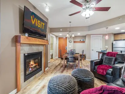a living room with a fireplace and a dining room at Fraser Crossing 1BR Condo | Hot Tub Access + Walk to Lifts in Winter Park