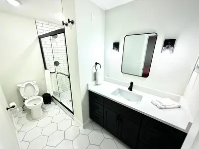 a bathroom with a sink and a toilet and a mirror at Family Fun Hub - Games, Hot Tub, Putting Greens in Centennial