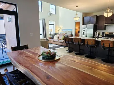 a kitchen and living room with a wooden table at 4th Street Alpine Loft - New - Central Ski Hub - King Bed, Garage Parking, Hot Tub, Great Location in Silverthorne