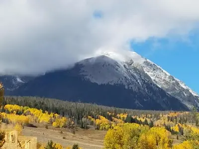 a snow covered mountain in the distance with trees at 4th Street Alpine Loft - New - Central Ski Hub - King Bed, Garage Parking, Hot Tub, Great Location in Silverthorne