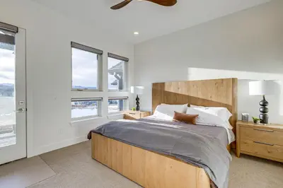 a bedroom with a bed with a wooden headboard and windows at Hot Tub and Amazing Views Luxury Winter Park Haven! in Winter Park