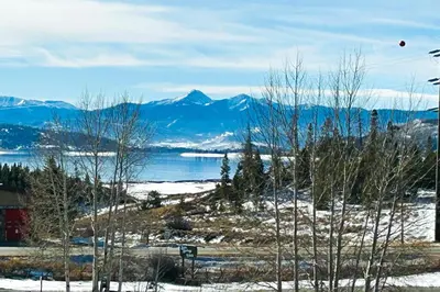 a group of trees in the snow with mountains in the background at Next To Nature in Grand Lake