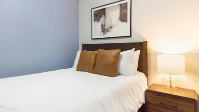 a bedroom with a bed with white sheets and a lamp at Landing Chic 1BD in Harvey Park South in Englewood