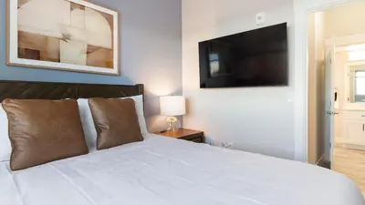 a bedroom with a white bed with a flat screen tv at Landing Chic 1BD in Harvey Park South in Englewood