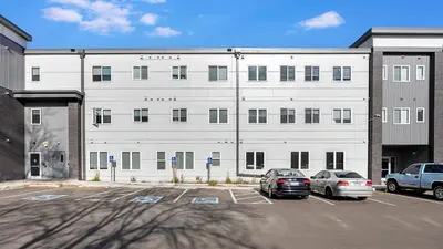 a large white building with cars parked in a parking lot at Landing Chic 1BD in Harvey Park South in Englewood