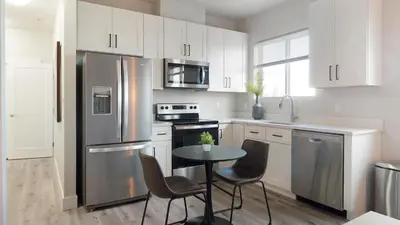 a kitchen with a stainless steel refrigerator and a table at Landing Chic 1BD in Harvey Park South in Englewood