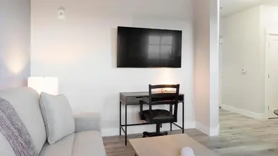 a living room with a couch and a television on a wall at Landing Chic 1BD in Harvey Park South in Englewood