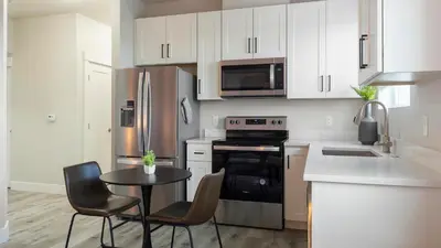 a kitchen with white cabinets and a table and chairs at Landing Chic 1BD in Harvey Park South in Englewood