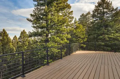 a wooden deck with a fence and trees at Great for Gatherings! Evergreen Getaway with Hot Tub in Evergreen