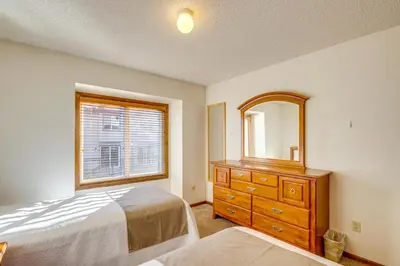 a bedroom with a bed and a dresser and a mirror at Steps to Free Ski Shuttle! Dtwn Winter Park Condo in Winter Park