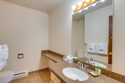 a bathroom with a sink and a toilet and a mirror at Steps to Free Ski Shuttle! Dtwn Winter Park Condo in Winter Park
