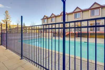 a fence with a swimming pool in front of a house at Steps to Free Ski Shuttle! Dtwn Winter Park Condo in Winter Park