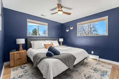 a bedroom with blue walls and a bed with two windows at Haus Vango in Arvada