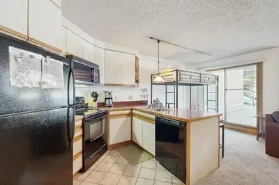 a kitchen with white cabinets and a black refrigerator at Iron Horse Resort #C1083 in Winter Park