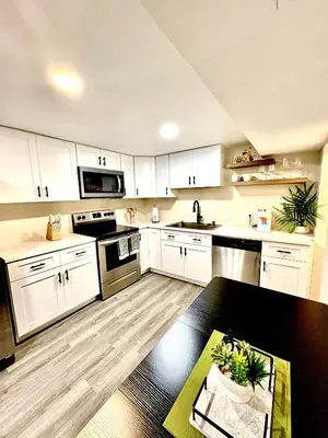 a kitchen with white cabinets and a black table at Private Residence Below Basement in Thornton