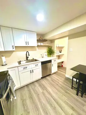 a kitchen with white cabinets and a sink and a table at Private Residence Below Basement in Thornton