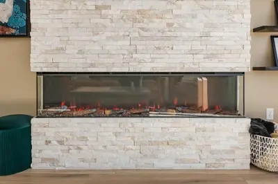 a stone fireplace with red flames in a living room at The Fox Den: Cozy & Fun with Amazing Views in Fraser