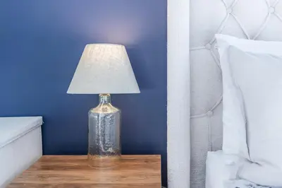 a glass vase with a lamp on a table next to a bed at The Fox Den: Cozy & Fun with Amazing Views in Fraser