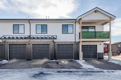 a house with two garage doors and a balcony at The Fox Den: Cozy & Fun with Amazing Views in Fraser