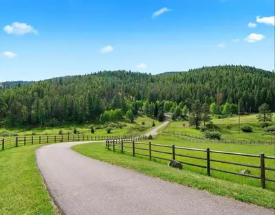 a winding road in a field with a fence at Modern barn by the creek in Evergreen