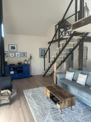 a living room with a blue couch and a staircase at Modern barn by the creek in Evergreen