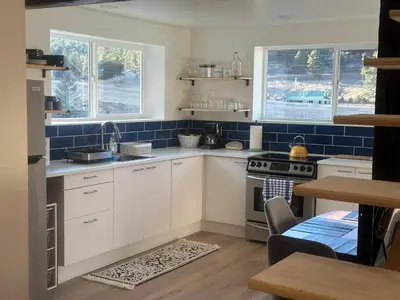 a kitchen with white cabinets and blue tiles at Modern barn by the creek in Evergreen