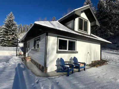 a small house with two chairs in the snow at Modern barn by the creek in Evergreen