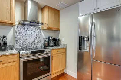 a kitchen with a stainless steel refrigerator and wooden cabinets at Group Getaway 3 Mi to Cherry Creek State Park! in Aurora