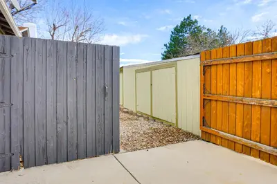 a fence with a wooden gate next to a sidewalk at Group Getaway 3 Mi to Cherry Creek State Park! in Aurora