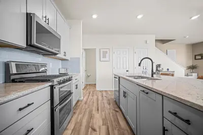 a kitchen with white cabinets and stainless steel appliances at 10 min to DIA, Walk to the Gaylord! in Aurora