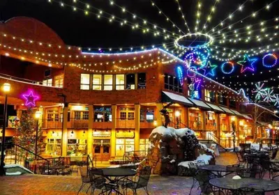a building with christmas lights and tables and chairs at Downtown Luxury + Hot Tubs; Walkable Winter Park in Winter Park
