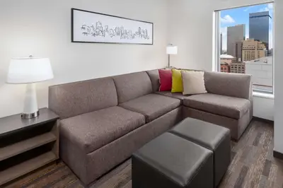 a living room with a brown couch and a window at Hyatt House Denver Downtown in Denver