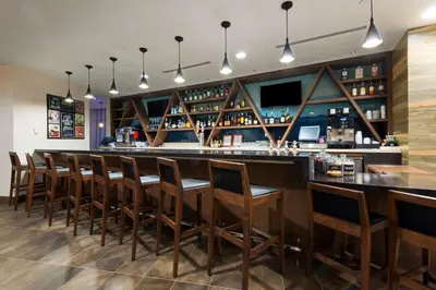 a bar with a row of wooden bar stools at Hyatt House Denver Downtown in Denver