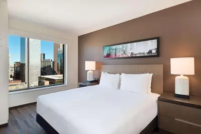 a bedroom with a large bed and a large window at Hyatt House Denver Downtown in Denver