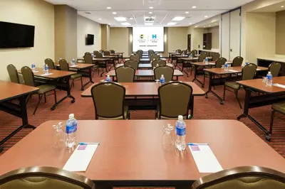 a room filled with tables and chairs with water bottles on them at Hyatt Place Denver Downtown in Denver