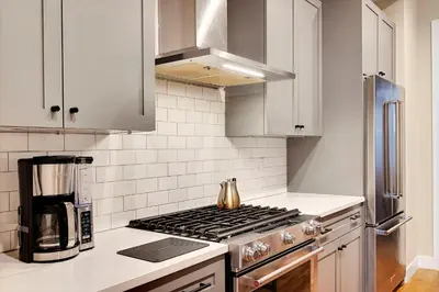 a kitchen with white cabinets and a stove top oven at Townhouse in Santa Fe Arts District in Denver
