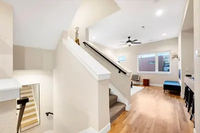 a white staircase in a home with white walls and wood floors at Townhouse in Santa Fe Arts District in Denver