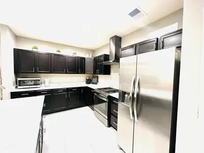 a kitchen with black cabinets and a stainless steel refrigerator at Entire Fully Equipped Basement Guest Apartment Home in DEN