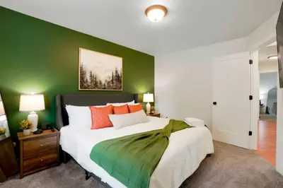 a bedroom with a large bed with a green wall at Game Room • Fire Pit • Arcade • Outdoor Dining in Arvada