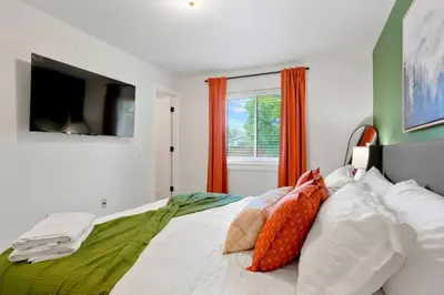 a bedroom with a bed with orange curtains and a television at Game Room • Fire Pit • Arcade • Outdoor Dining in Arvada